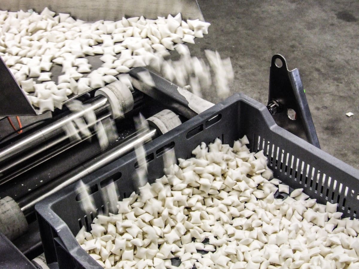 Loading gum pellets into a plastic crate using a vibratory feed chute